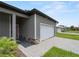 Exterior view of a gray home featuring a two-car garage, stone accents, and a paved driveway at 1790 New London St, North Port, FL 34288