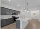 Modern kitchen with gray cabinets, stainless steel appliances, an island with quartz countertop, and wood-style tile flooring at 1790 New London St, North Port, FL 34288