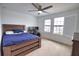 Bedroom with a ceiling fan, carpet flooring and a wooden bed in front of bright windows with shutters at 2208 Darley Oak Way, North Port, FL 34289