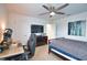 Well-lit bedroom with ceiling fan, desk, and queen bed, adjacent to the entry and closet doors at 2208 Darley Oak Way, North Port, FL 34289
