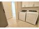 Well-lit laundry room featuring tile floors, cabinets and white washer and dryer machines at 2208 Darley Oak Way, North Port, FL 34289