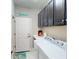 A well-lit laundry room with washer, dryer, and dark upper cabinets at 2444 Daisy Dr, North Port, FL 34289