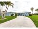 Single-story home with mature palm trees, lush green lawn and inviting driveway at 936 Lassino Ct, Punta Gorda, FL 33950