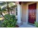 Front exterior of home with a red front door, white column and bushes next to a mature palm tree at 1675 Blue Lake Cir, Punta Gorda, FL 33983