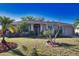 Inviting single-story home featuring a manicured lawn, mature palms, and a welcoming covered entrance at 1675 Blue Lake Cir, Punta Gorda, FL 33983