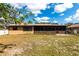 View of the house with a screened-in back porch in a spacious backyard with trees and sunny blue skies at 2281 Tolbert St, Port Charlotte, FL 33948