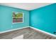 A bright bedroom with a large window, aqua painted walls, and wood-look flooring, for a calming feel at 23227 Adela Ave, Port Charlotte, FL 33952