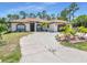 Charming single-Gathering home with a well-manicured lawn and a long driveway leading to an attached garage at 23227 Adela Ave, Port Charlotte, FL 33952
