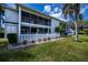 Back exterior view of the condo building, showing the yard with green lawn and trees at 1340 San Cristobal Ave # 305, Punta Gorda, FL 33983