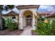 Elegant home entrance with arched doorway, lush landscaping, and a stone walkway at 14455 Silver Lakes Cir, Port Charlotte, FL 33953