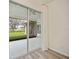 Covered lanai view through sliding glass doors with a view of the landscaped yard and lake beyond at 14455 Silver Lakes Cir, Port Charlotte, FL 33953