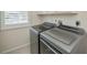 Modern laundry room with front load washer and dryer and a window with white shutters at 14455 Silver Lakes Cir, Port Charlotte, FL 33953
