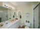 Well-lit bathroom featuring dual sinks, vanity lighting, and glass-enclosed shower at 19335 Water Oak Dr # 202, Port Charlotte, FL 33948