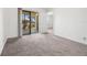 Bright bedroom with neutral carpet, access to a balcony, and a view of the outdoor landscape at 19505 Quesada Ave # Ee204, Port Charlotte, FL 33948