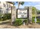 Entrance to The Oaks IV featuring a welcome sign framed by brick columns and lush foliage at 19505 Quesada Ave # Ee204, Port Charlotte, FL 33948