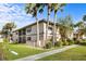 Exterior view of condo with mature palms, well-maintained lawn, and a charming screened-in porch at 19505 Quesada Ave # Ee204, Port Charlotte, FL 33948