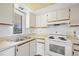 Well-lit kitchen with a double sink, white cabinets, and modern electric range, perfect for cooking at 19505 Quesada Ave # Ee204, Port Charlotte, FL 33948