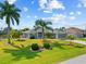 The front yard of the house features mature palm trees, manicured shrubs, and colorful mulch flower beds at 27191 Tierra Del Fuego Cir, Punta Gorda, FL 33983