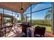 Enclosed sunroom with a grill, patio furniture, and views of the lush backyard at 29175 River Dr, Punta Gorda, FL 33982