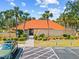 Charming community clubhouse with an orange roof, lush landscaping, and accessible parking spaces at 3006 Caring Way # 431, Port Charlotte, FL 33952