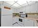 Functional kitchen featuring white appliances and ample counter space under bright, grid-patterned lighting at 3006 Caring Way # 431, Port Charlotte, FL 33952