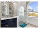 Bright bathroom features walk-in shower, dark vanity, decorative mirror, and a scenic view at 13000 Windcrest Dr, Port Charlotte, FL 33953