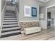 Inviting entryway with patterned stairs, stone accent wall, bench, and view to the laundry room at 13000 Windcrest Dr, Port Charlotte, FL 33953