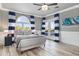 Nautical themed main bedroom with wood-look tile flooring and a balcony overlooking a lush landscape at 13000 Windcrest Dr, Port Charlotte, FL 33953