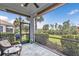Relaxing screened-in lanai with ceiling fan, and view of the beautifully landscaped backyard with palm trees at 2892 Myakka Creek Ct, Port Charlotte, FL 33953
