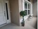 Inviting front porch featuring a white front door, textured walls, and decorative potted plants near the window at 1210 Nabatoff St, North Port, FL 34288