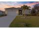 Charming single-story home with a well-manicured lawn, palm tree, and a two-car garage at 122 Glades Dr, Rotonda West, FL 33947