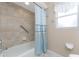 Bathtub and shower combo featuring tiled walls, grab bar, patterned shower curtain and natural light from a window at 15090 Buswell Ave, Port Charlotte, FL 33953