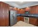 Bright kitchen featuring stainless steel appliances, dark countertops, tile flooring, and lots of cherry-toned cabinetry at 17495 Boca Vista Rd # 6, Punta Gorda, FL 33955