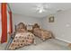 Guest bedroom featuring two twin beds, a ceiling fan, and a window with orange curtains at 18536 Alphonse Cir, Port Charlotte, FL 33948