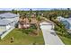 Single-story home featuring a manicured lawn, mature palm trees, mulch beds and long concrete driveway at 18536 Alphonse Cir, Port Charlotte, FL 33948