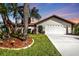 Charming single-story home with an attached two-car garage, well-maintained landscaping and mulch beds, and a long driveway at 18536 Alphonse Cir, Port Charlotte, FL 33948