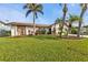Well maintained home featuring a large manicured lawn, mature palm trees, and elegant stone accents at 18536 Alphonse Cir, Port Charlotte, FL 33948