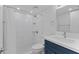 Bathroom featuring tiled shower with marble design, updated fixtures, and dark blue vanity at 19505 Quesada Ave # Ss102, Port Charlotte, FL 33948