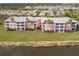 Aerial view of a pink residential complex with palm trees, a pond and lush green lawn in front at 2040 Willow Hammock Cir # 208, Punta Gorda, FL 33983