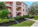Exterior shot of a pink condo building with stairs and tidy landscaping at 2040 Willow Hammock Cir # 208, Punta Gorda, FL 33983