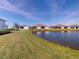Scenic backyard view of residences overlooking a serene pond with lush green surroundings on a bright day at 24313 Westgate Blvd, Punta Gorda, FL 33980