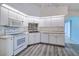 Well-lit kitchen featuring white appliances and cabinets, backsplash, and plank flooring at 429 Dorchester St, Port Charlotte, FL 33954