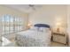 Comfortable bedroom features a ceiling fan, large window and matching wicker bedside tables with lamps at 432 Sunset Lake Blvd # 203, Venice, FL 34292