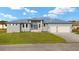 Beautiful gray home featuring a three-car garage, well-manicured lawn, and blue-gray trim at 7363 N Moss Rose, Punta Gorda, FL 33955