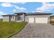 Gray home with a paved driveway, a manicured front lawn, and a three-car garage at 7363 N Moss Rose, Punta Gorda, FL 33955