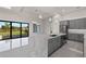Open kitchen with gray cabinets, quartz counters, stainless appliances, and sliding glass doors to the backyard at 7363 N Moss Rose, Punta Gorda, FL 33955