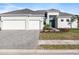 Beautiful single-story home with a three-car garage and gray brick driveway at 8604 Shore Lake Dr, Englewood, FL 34224