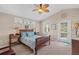 Cozy bedroom with a wooden bed frame, neutral walls, three sunny windows, and a ceiling fan at 12492 Shimmering Oak Cir, Venice, FL 34293