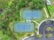 This aerial view shows tennis courts in a well-maintained community with lush landscaping and a nearby parking area at 12492 Shimmering Oak Cir, Venice, FL 34293