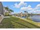 Lush green backyard featuring a waterfront with a boat lift, seawall, and tropical landscaping under a sunny sky at 1303 Casey Key Dr, Punta Gorda, FL 33950